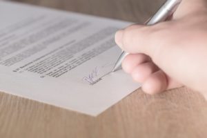 A Person Signing on a Piece of Paper With a Pen