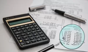Image of a calculator, magnifying glass, pen, and financial statement depicting the actions Schlanger Law Group will take to help minimize the impact of identity theft on victims
