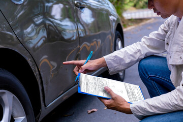 Photo of an insurance adjuster examining a car scratch to determine if a car lease damage waiver provides coverage