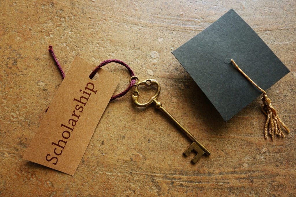 A key and a graduation cap with the word scholarship.