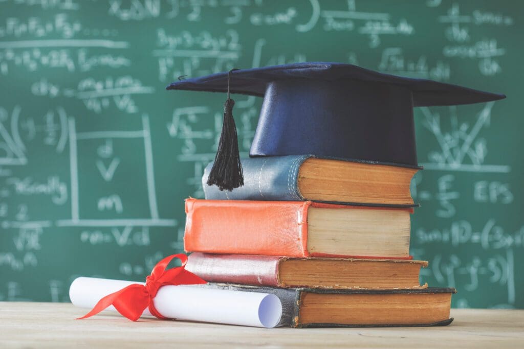 A stack of books with a graduation cap on top.