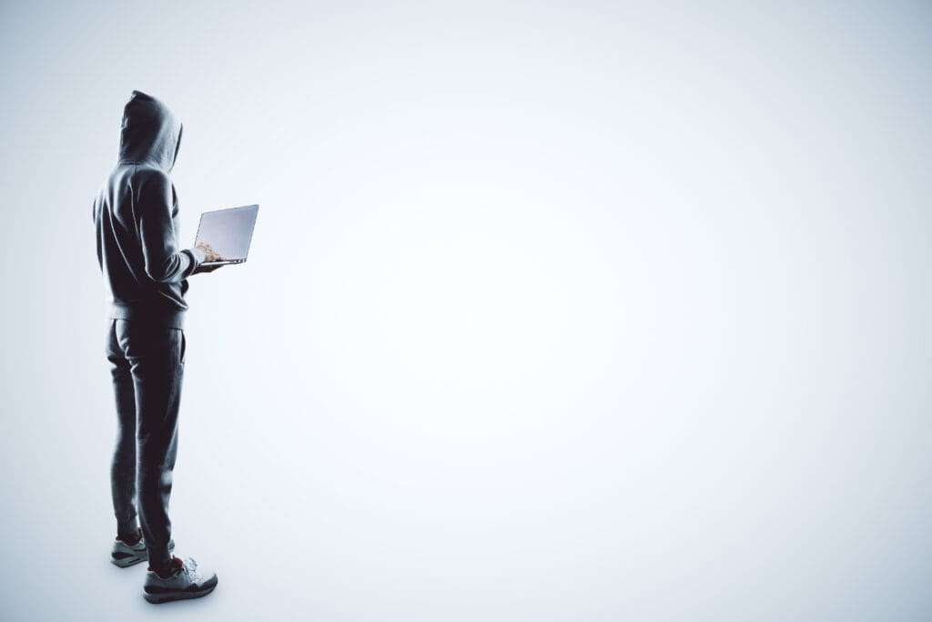 Man in hoodie using laptop on white background.